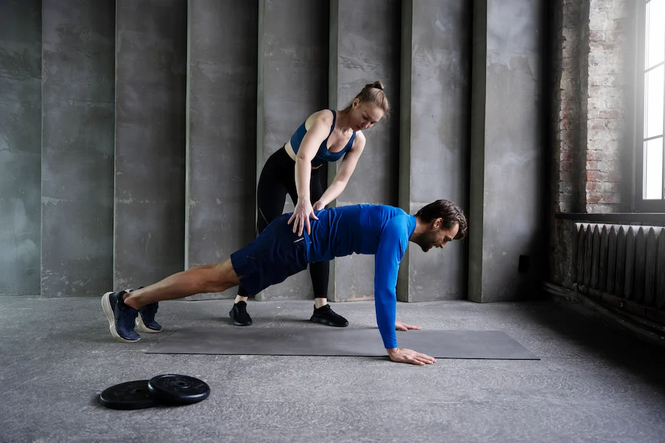 mujer guiando al hombre a hacer entrenamiento funcional